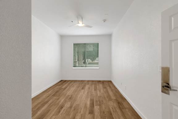 A room with wooden flooring and a window with blinds.