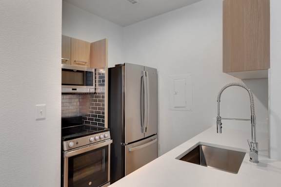 A kitchen with a stove, oven, refrigerator, and sink.