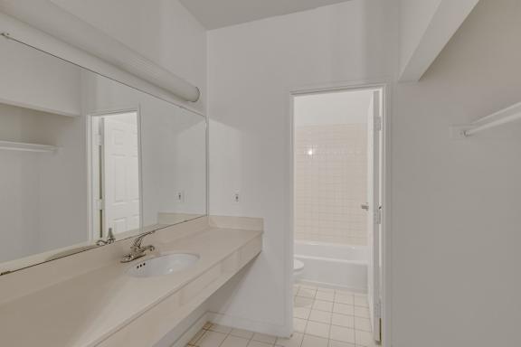 White bathroom with a sink and mirror at AVIA Apartments On Alpha, Dallas, 75240