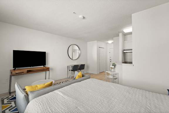A bedroom with a bed, a television, and a mirror on the wall.
