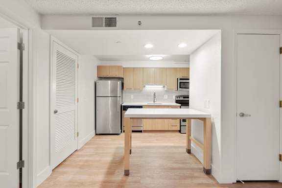 A kitchen with a white countertop and wooden cabinets. at AVIA Lofts on Parkway, Vancouver Washington