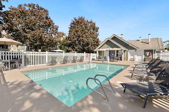 A swimming pool surrounded by lounge chairs and trees. at AVIA Lofts on Parkway, Washington