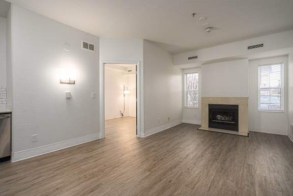 Large empty room with a fireplace and wood flooring at AVIA Lofts on Victors Way, Michigan