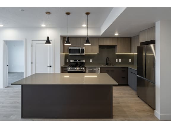 Modern kitchen island with pendant lighting and wood cabinetry at Brickside Heights Apartments, Millcreek, 84106