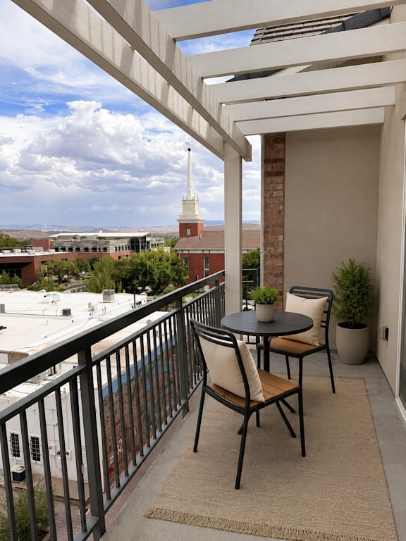 A balcony with a table and chairs overlooking a cityscape.