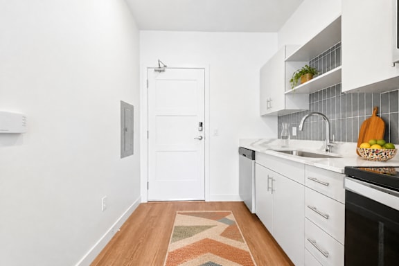 A kitchen with white cabinets and a rug on the floor.