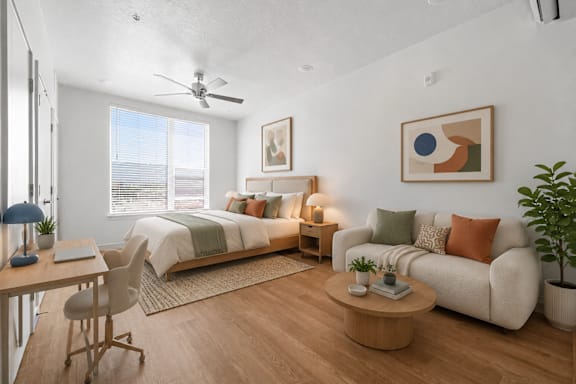 A modern bedroom with a large bed, a couch, a desk, and a ceiling fan.