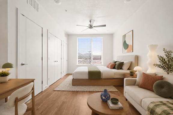 A well-lit, modern bedroom with a bed, couch, and a ceiling fan.