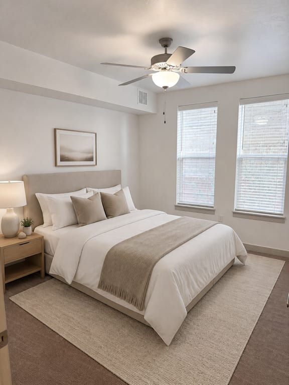 A bedroom with a large bed and a ceiling fan.