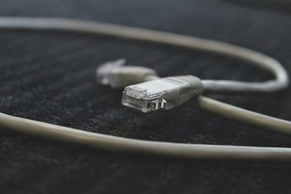 A white Ethernet cable with a RJ45 connector on one end and a twisted pair of wires on the other end.