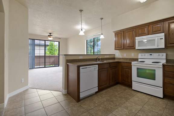 A kitchen with white appliances and brown cabinets at Siena Villas Apartments, Orem, Utah