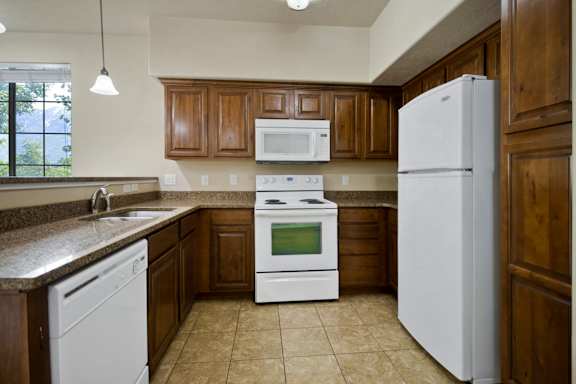 A kitchen with white appliances and brown cabinets at Siena Villas Apartments, Orem, 84097