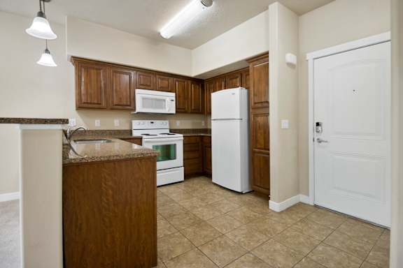 A kitchen with white appliances and wooden cabinets at Siena Villas Apartments, Orem, 84097