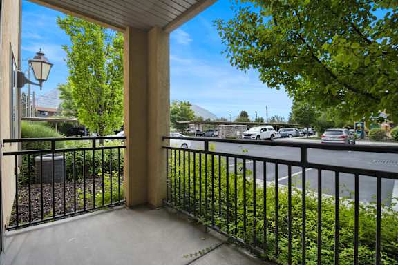 A view from a balcony looking out at a street with cars and trees. at Siena Villas Apartments, Utah, 84097