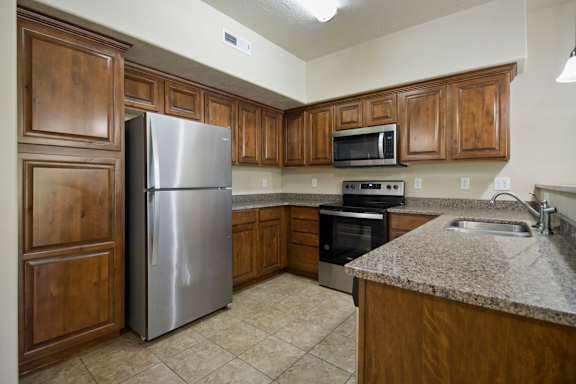 A kitchen with a stainless steel refrigerator and wooden cabinets. at Siena Villas Apartments, Apartments, Orem, UT