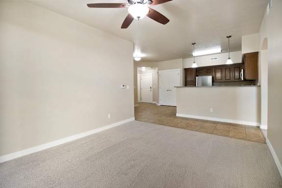 A spacious room with a ceiling fan and a kitchen area in the background. at Siena Villas Apartments, Orem