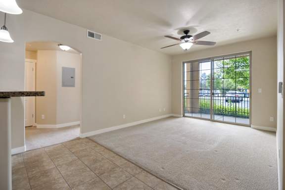 A spacious living room with a ceiling fan and sliding glass doors leading to a balcony at Siena Villas Apartments, Orem, 84097