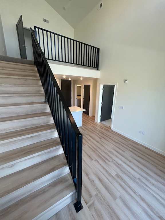 A staircase with wooden steps and black railings leads to a bright room.