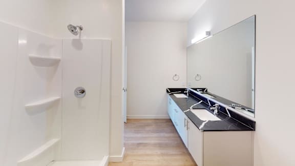 A bathroom with a sink, mirror, and shower.