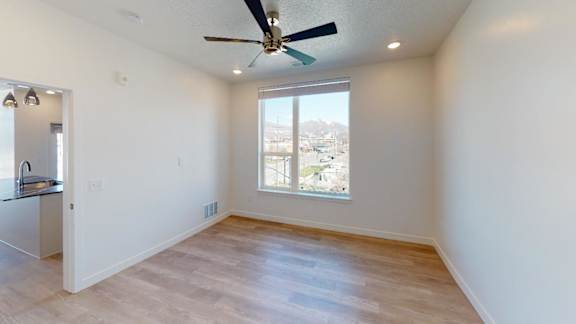A room with a ceiling fan and a window overlooking a cityscape.