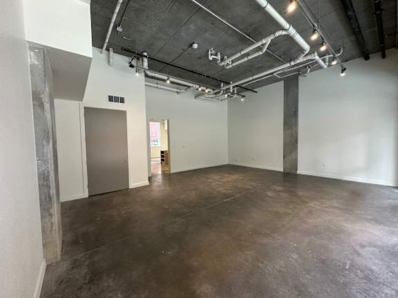 A large empty room with concrete floors and walls, and a ceiling with exposed pipes at Paperbox Lofts Apartments, Utah, 84101