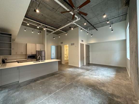 A large, empty room with a kitchen area on the left side at Paperbox Lofts Apartments, Salt Lake City  , 84101