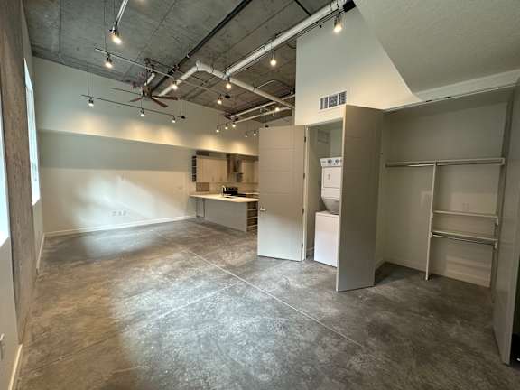 A large, empty room with a kitchenette and a refrigerator at Paperbox Lofts Apartments, Utah