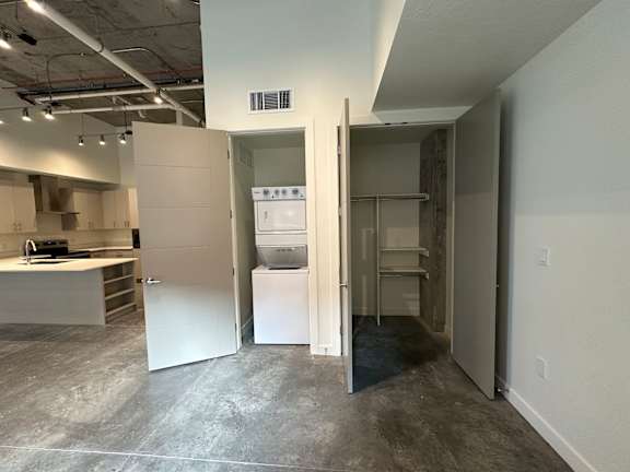 A kitchen area with a sink, stove, and refrigerator in a room with a concrete floor at Paperbox Lofts Apartments, Utah