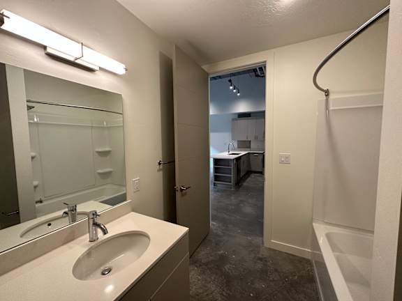 A bathroom with a sink, mirror, and bathtub. at Paperbox Lofts Apartments, Utah, 84101
