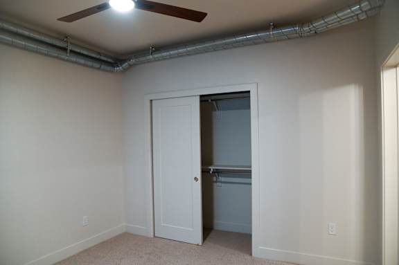 A room with a ceiling fan and a door leading to another room.