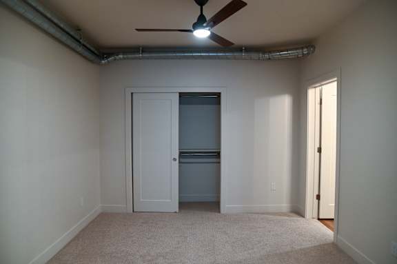 A room with a ceiling fan and a door.
