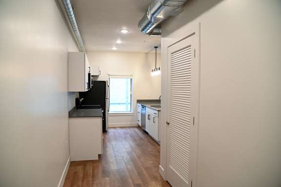 A kitchen with a black fridge and white cabinets.