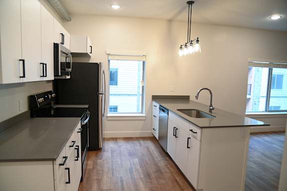 A kitchen with black appliances and white cabinets.