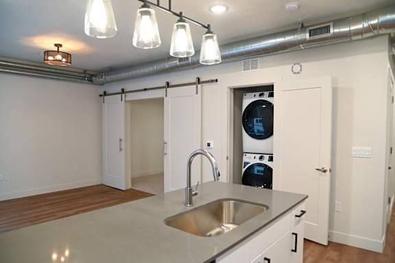 A modern kitchen with a stainless steel sink and white cabinets.