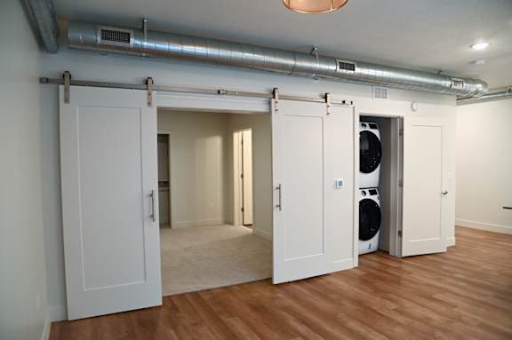 A room with white doors and a washing machine in the back.