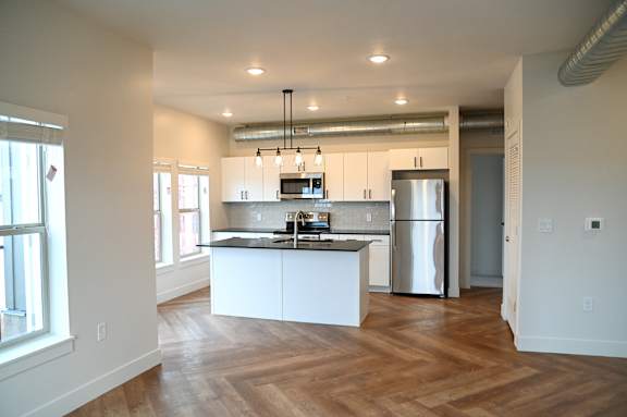 Open kitchen with white island and exposed ductwork at The Revival Apartments, Utah, 84101