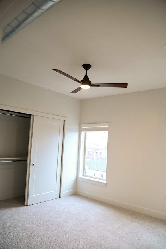 Empty bedroom with ceiling fan and closet at The Revival Apartments, Utah