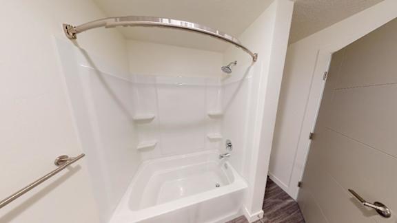 A white bathtub with a shower head and a grab bar. at Paperbox Lofts Apartments, Apartments, Salt Lake City  , UT