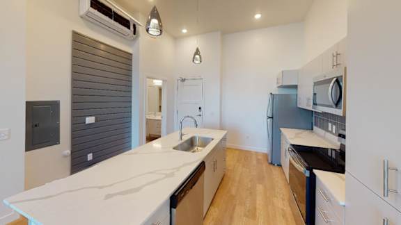 A modern kitchen with a white countertop and stainless steel appliances.