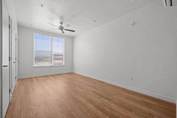 Empty room with wooden floor and ceiling fan.