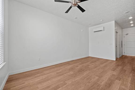 A room with a ceiling fan and wooden flooring.