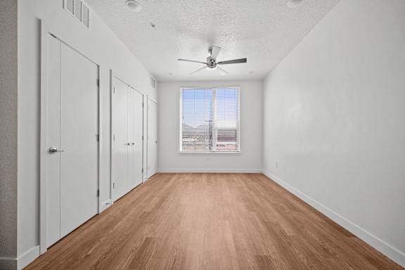 A room with a ceiling fan and a window with blinds.