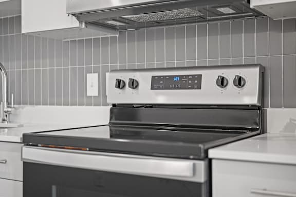 A modern kitchen with a stove top oven and a tile backsplash.