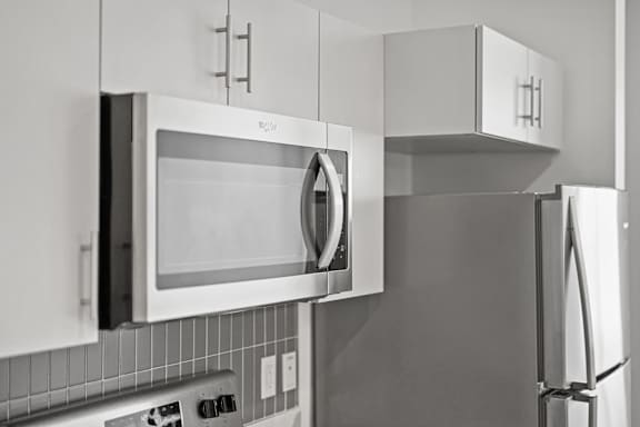 A black and white photo of a kitchen with a microwave and refrigerator.
