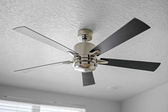 A ceiling fan with five blades is hanging from the ceiling.