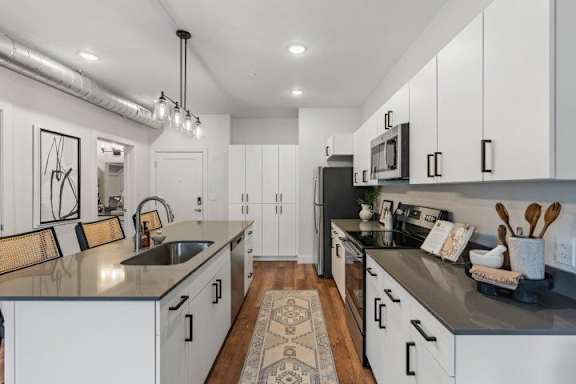 A modern kitchen with white cabinets and a black countertop. at The Revival, Salt Lake City, 84101