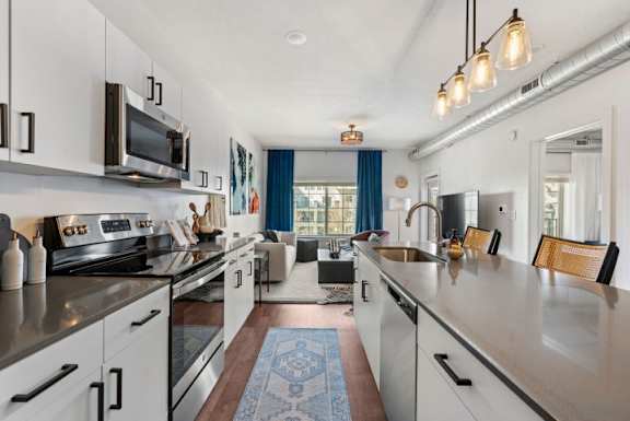 A modern kitchen with white cabinets and a blue rug on the floor.