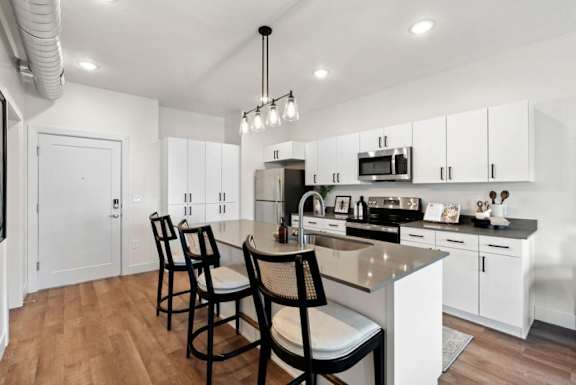 A kitchen with white cabinets and a wooden floor.