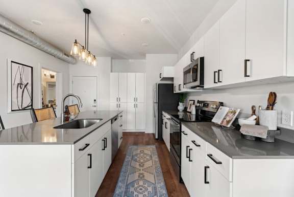 A kitchen with white cabinets and a black countertop.