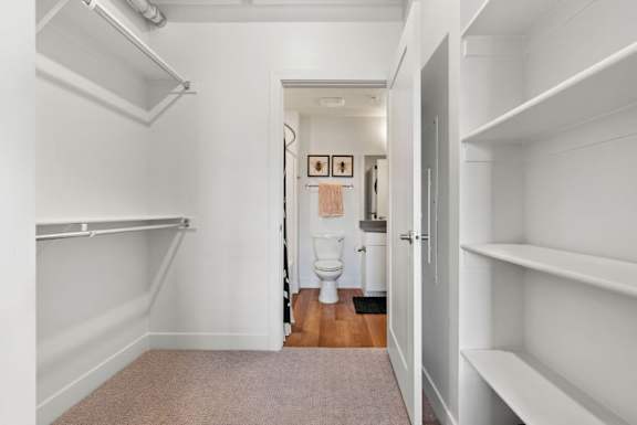 A white hallway with a toilet in the distance.